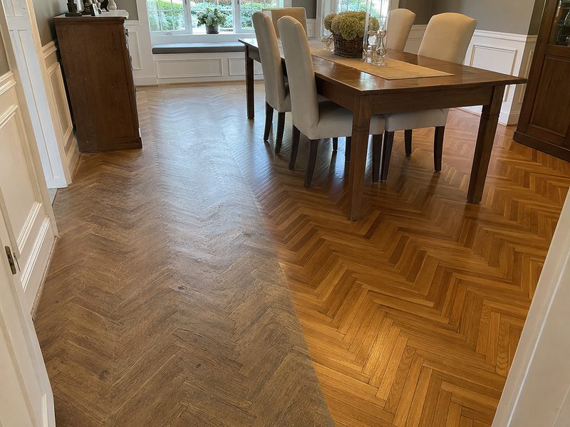 Herringbone hardwood dining room floor, worn finish on the left and refinished on the right